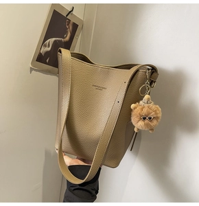 Detail of khaki pebbled leather bucket bag featuring a cute plush charm with sunglasses