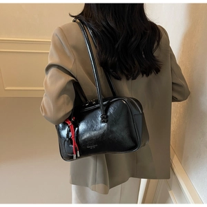 Vue détaillée du sac bowling noir brillant avec logo embossé et cordon rouge décoratif