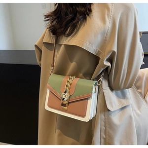 Detail of color-block crossbody bag with gold chain decoration on trench coat outfit