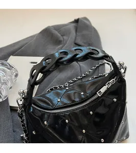 Close-up of black quilted leather handbag with silver rivets and metal chain details