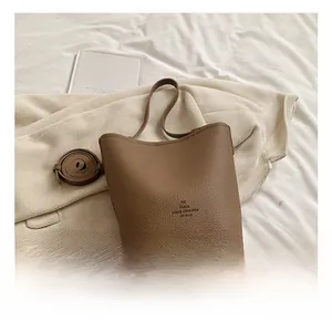 Detail showing the brown litchi grain texture and elegant bow logo on this bucket bag