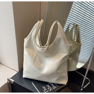 Detail view of cream white tote bag featuring geometric patchwork and dual straps