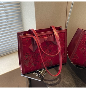 Detail of red bridal tote bag featuring large bow and exquisite floral embroidery texture