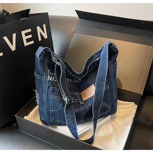 Detail der dunkelblauen Denim-Tragetasche mit verstellbarem Gurt in einer Geschenkbox