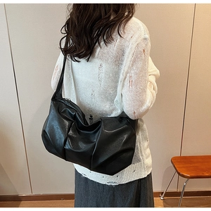 Detail of black pleated cloud shoulder bag showing soft faux leather texture and slouchy design