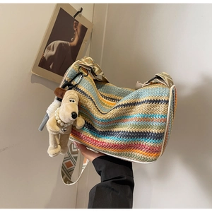 Close-up of a rainbow woven cylinder bag with colorful wave patterns and a dog charm