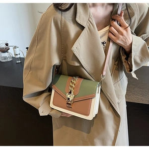 Detail of color-block flap bag with gold chain decoration and metallic push-lock