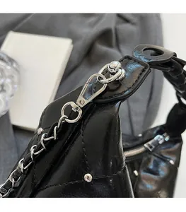 Close-up of polished silver chain hardware and pleated black leather texture on bag