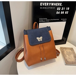 Detail of blue denim flap and litchi faux leather with butterfly metal buckle and drawstring