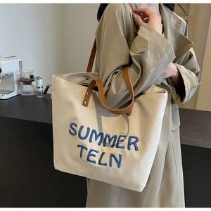 Détail du sac cabas en toile épaisse avec broderie bleue Summer Teln et anses en cuir marron