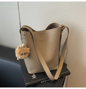 Detail of khaki pebbled leather bucket bag with cute plush sunglasses cat pendant