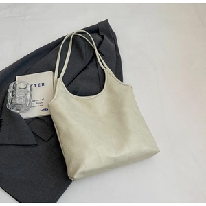 Close-up of cream-colored tote bag featuring geometric patchwork and fine stitching