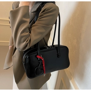 Détail du sac bowling en cuir brillant noir avec breloque cœur rouge et double fermeture