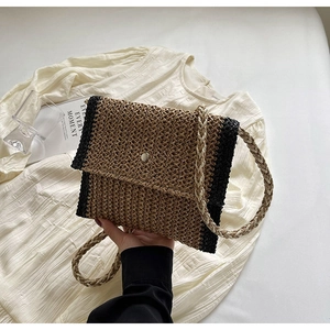 Dettaglio di una borsa a busta in paglia intrecciata con fibbia argento e trama a contrasto