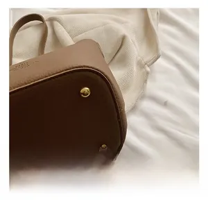 Macro view of brown lychee grain leather bucket bag featuring gold metal bottom studs