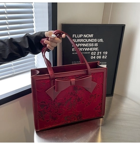 Detail of burgundy bridal handbag with floral embroidery and large leather bow