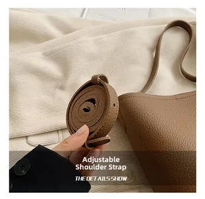 Close-up of adjustable shoulder strap on brown lychee texture leather bucket bag