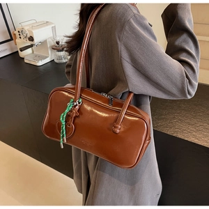 Vue détaillée d'un sac bowling en cuir marron foncé avec doubles anses et breloque en cœur