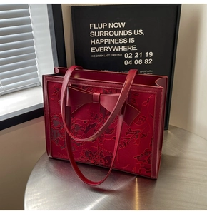 Detail of dark red bridal tote bag featuring floral embroidery and a large bow decor