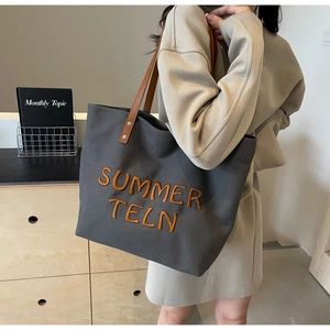 Détail du grand sac cabas en toile gris foncé avec broderie et anses en cuir