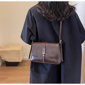 Detail view of vintage dark brown faux leather crossbody bag with metallic gold buckle