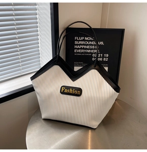 Macro shot of contrasting black and white tote bag with pleated texture and gold logo label