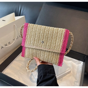 Dettaglio macro della borsa a busta in paglia intrecciata con accenti rosa e fibbia