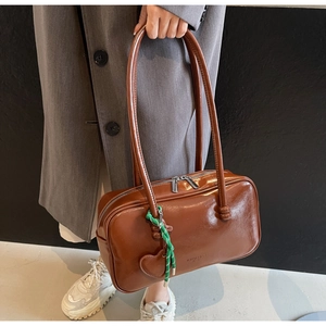 Détail du sac bowling marron brillant avec corde tressée verte et étiquette cœur