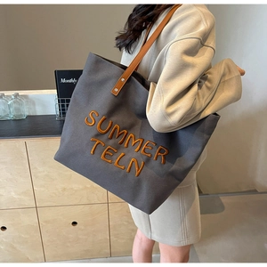 Gros plan d'un sac cabas en toile avec broderie orange et bandoulières en cuir