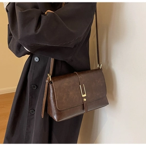 Macro shot showing retro brown leather texture and elegant gold metal buckle on flap