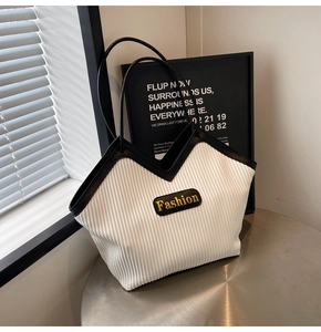 Detail of pleated tote bag with black leather trim and gold Fashion logo plaque