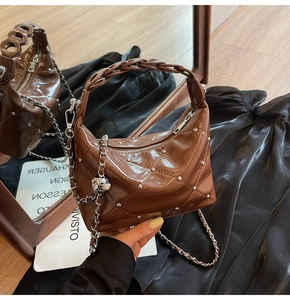 Close-up of brown quilted leather bag with silver studs and woven handle detail