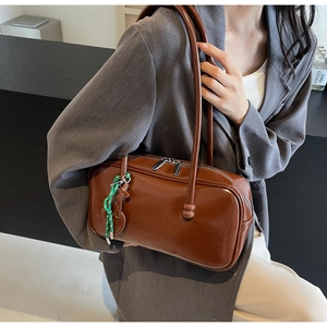Détails du sac bowling brillant caramel avec longue bandoulière et pendentif vert tressé