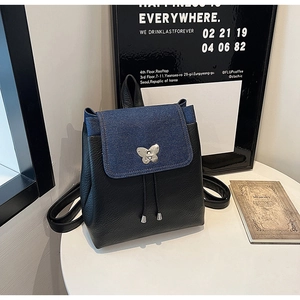 Detail of blue denim and black leather backpack with butterfly metal clasp and drawstring