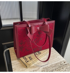 Detailed close-up of red jacquard wedding tote bag with floral embroidery and bow