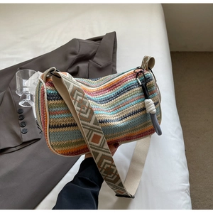 Detail of colorful woven shoulder bag with geometric jacquard strap on a white bed