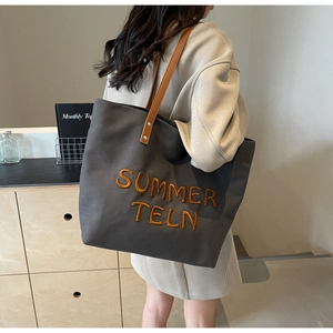 Gros plan du sac cabas en toile anthracite avec broderie et anses en cuir