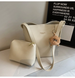 Detail of cream white lychee leather tote bag set with a mini sunglasses pom-pom charm