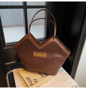 Detail of brown tote bag featuring unique pleated texture and Fashion leather label