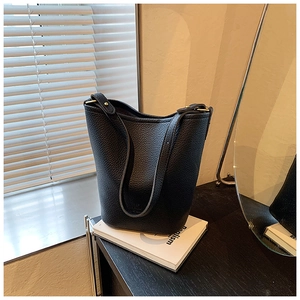 Detailed view of black litchi texture leather bucket bag with wide shoulder strap