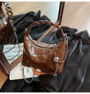 Detailed view of deep brown quilted patent leather bag with silver rivets and chain