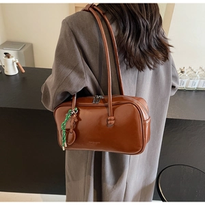 Détail d'un sac bowling en cuir huilé marron avec fine bandoulière et gaufrage latéral