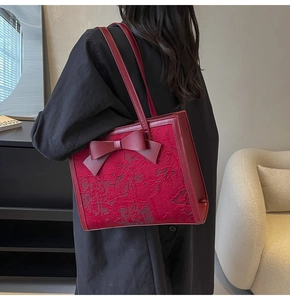 Close-up of elegant red bridal tote bag featuring jacquard floral and bow detail