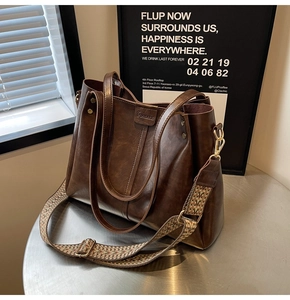 Détail du sac cabas vintage en cuir marron avec bandoulière tissée et rivets en métal