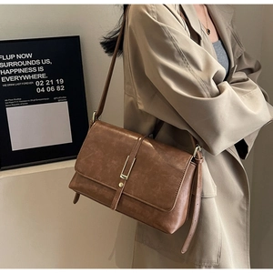 Detail of vintage brown leather underarm bag with metal buckle and shoulder strap