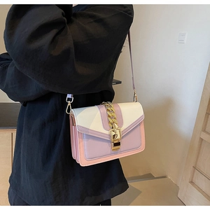 Detail of color-block crossbody bag with gold chain buckle worn on shoulder