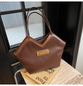 Detail of dark brown tote bag showing vertical pleated texture and V-shaped top design