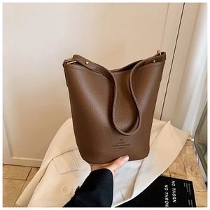 Close-up of brown pebbled leather bucket bag featuring elegant gold metal hardware details