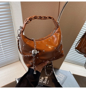 Detail of brown glossy quilted handbag with silver studs and chain decoration