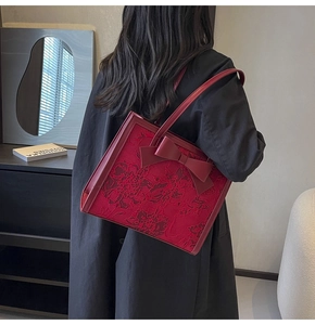 Detail of red bridal handbag featuring elegant floral embroidery and a large 3D bow